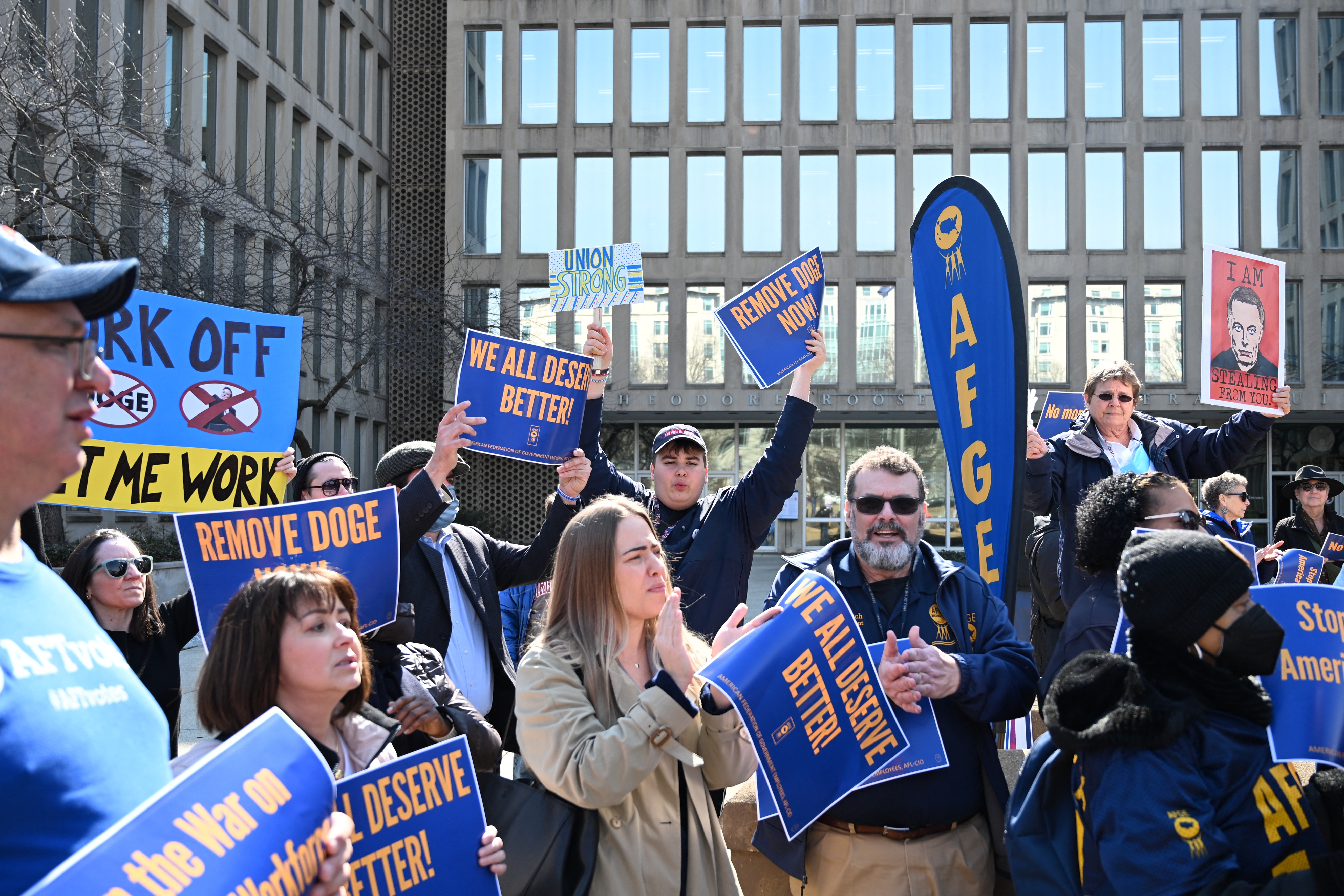 Protesters hold signs in solidarity with the American Federation of Government Employees at a March 4 rally in support of federal workers at the Office of Personnel Management in Washington, D.C.