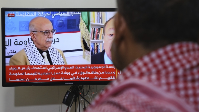 A man watches the news on TV, displaying footage of Ahmed al-Rahawi, the prime minister of the Houthi-controlled government, who was killed, along with others, in Thursday's Israeli strikes on the capital, in Sanaa, Yemen, Saturday, Aug. 30, 2025.