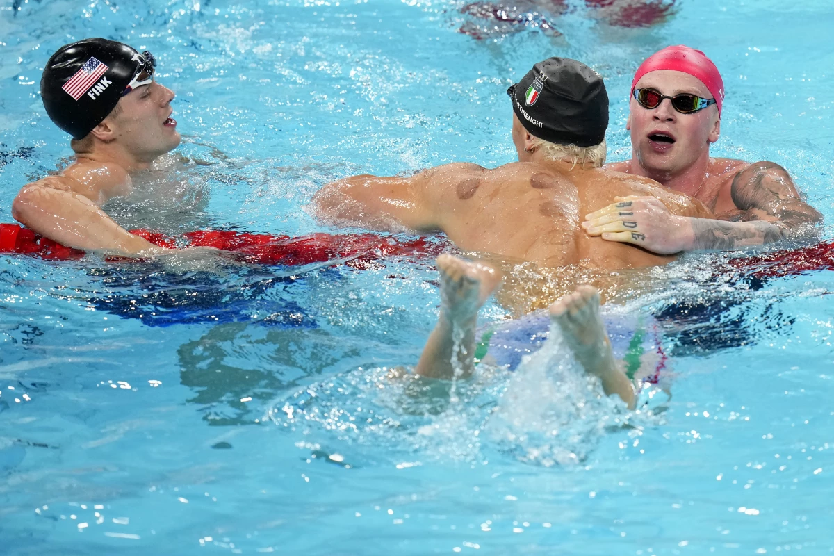 Nicolo Martinenghi, center, of Italy, is congratulated by Adam Peaty, of Great Britain, right, and Nic Fink, of the United States, left, after winning the men's 100-meter breaststroke final at the 2024 Summer Olympics on Sunday.
