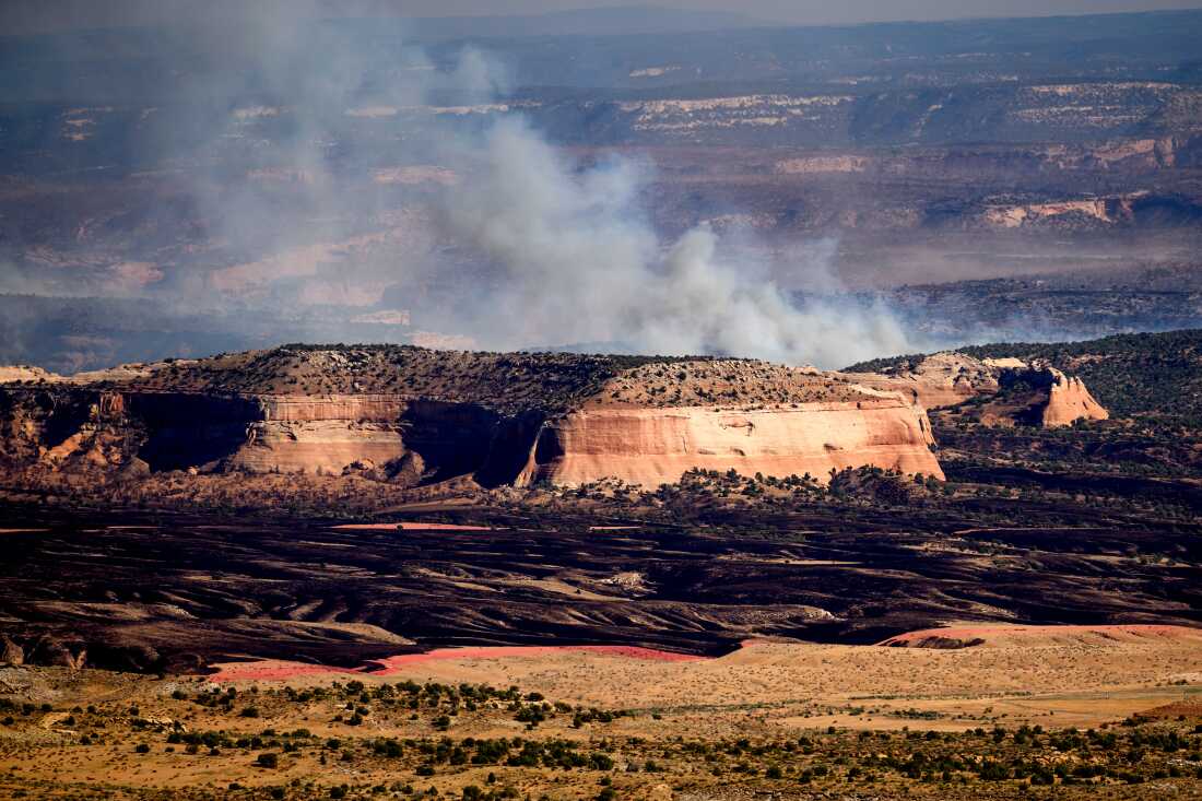 Smoke from the Snyder Fire appears over a tall rock formation near Thompson Springs, Utah, on June 28.