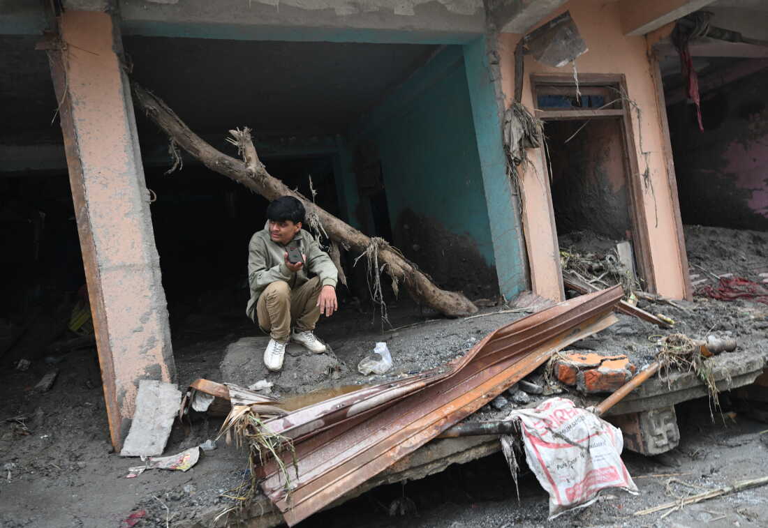 A man sits amidst debris of a house deluged in sludge following flash floods at Devighat in Nepal's Nuwakot district.