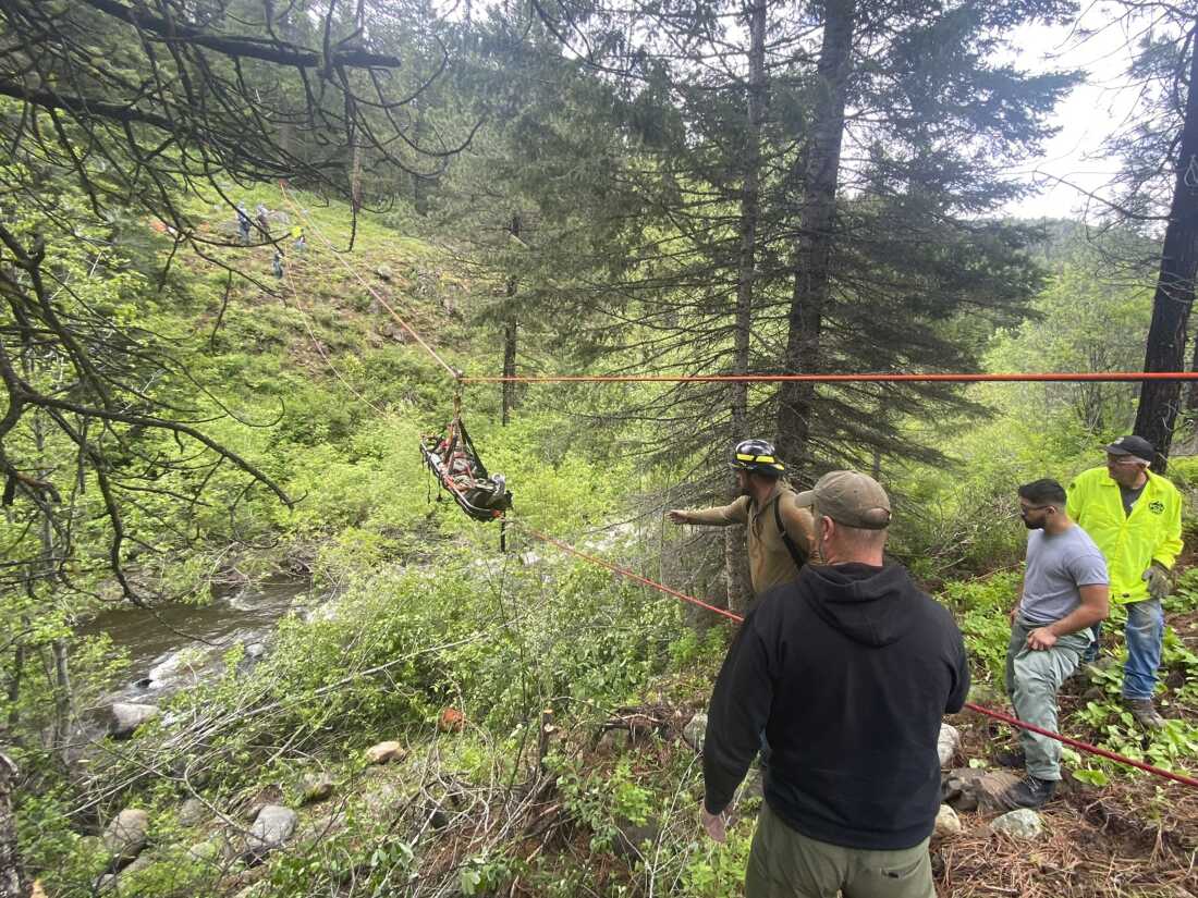 In this image provided by the Baker County Sheriff's Office, responders aid in rescue efforts after a vehicle went into an embankment on June 3, 2024, in Oregon. A dog helped his owner get rescued after the crash by traveling nearly four miles to the campsite where the man was staying with family, authorities said.