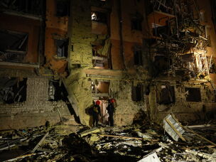 Rescue workers walk in front of a residential building damaged by a Russian airstrike in Zaporizhzhia, Ukraine, on Saturday.