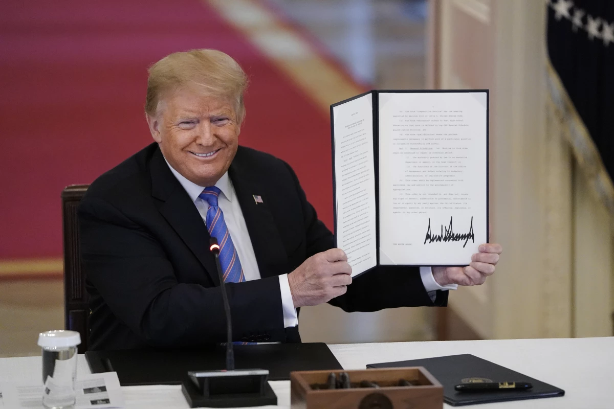 Then-President Donald Trump signs an executive order related to reforming the hiring process for federal jobs on June 26, 2020.