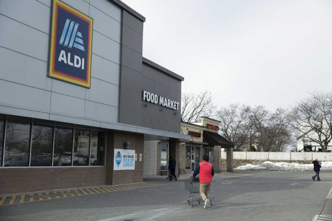 With his back to the camera, Henderson walks through the parking lot at Aldi to return his shopping cart to the grocery store.