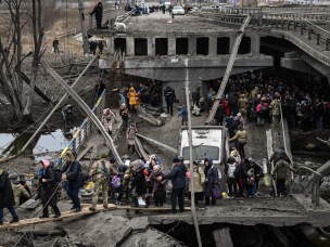 People cross a destroyed bridge as they evacuate Irpin, a suburb northwest of Kyiv, during heavy shelling and bombing on March 5, 2022.