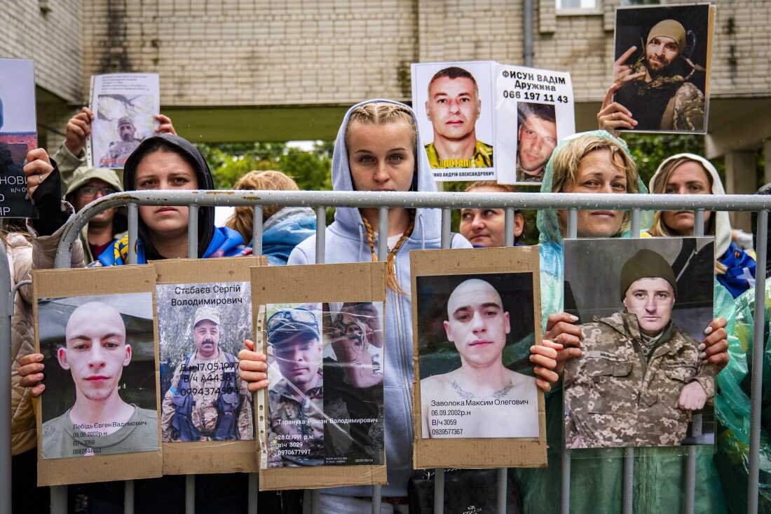 Ukrainians hold photos of their missing relatives as they watch freed Ukrainian soldiers arrive after a POW exchange with Russia in the Chernihiv region of nothern Ukraine on June 25, 2025.