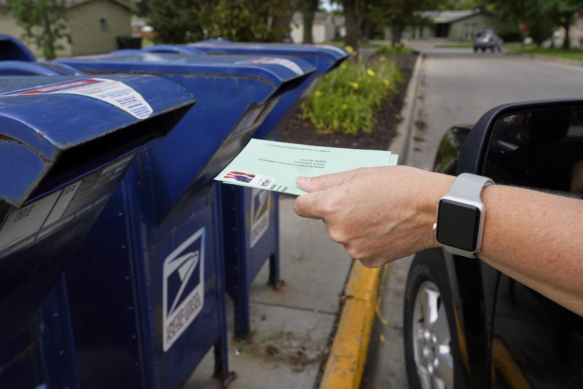 A person drops applications for mail-in-ballots into a mailbox in 2020 in Omaha, Neb.