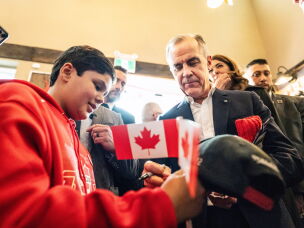 Canada's Prime Minister Mark Carney signs an autograph as he attends a national unity rally in Red Deer, Alberta, Oct. 16.