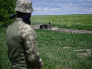 A Ukrainian serviceman controls a ground robot in a field test in the southeastern region of Zaporizhzhia in June. Ukraine is increasingly using ground drones for tasks that include delivering ammunition and medicine to front-line troops. Ukraine mounts machine guns on the robots to carry out attacks. The drones are also used to evacuate wounded soldiers in the dangerous kill zone.