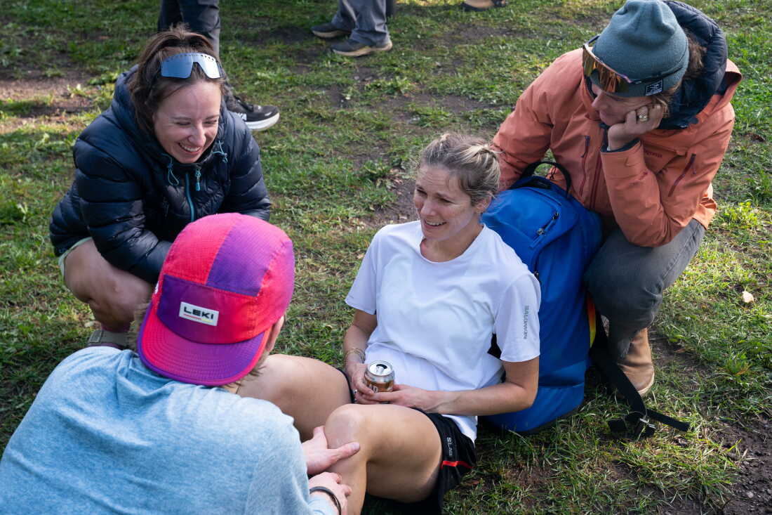 Diggins smiles and laughs with her crew as she rests on the ground at the finish line.