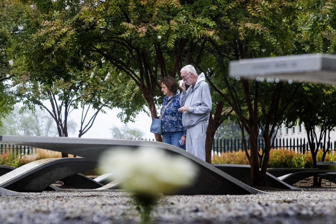 A man and woman stand near a memorial bench to read its nameplate at the National 9/11 Pentagon Memorial in Arlington, Virginia, on September 10, 2025.