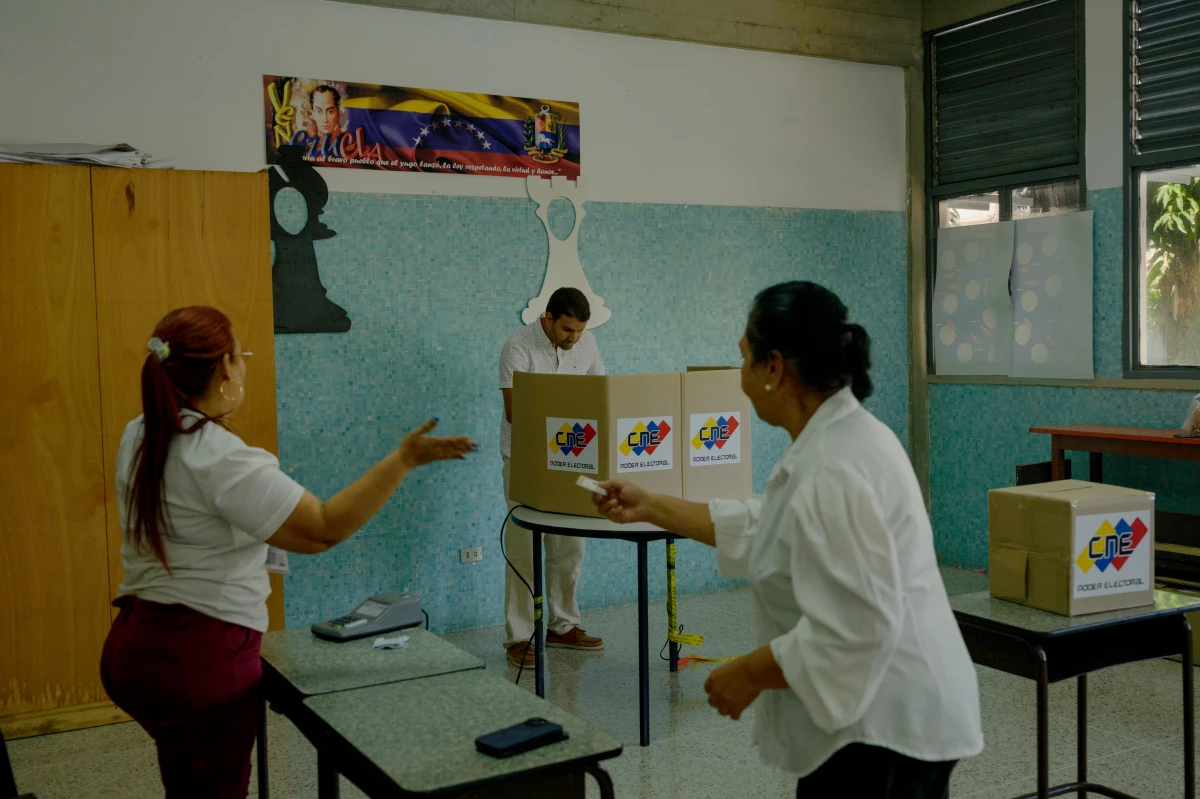 Election workers clap as the final person in the line votes at the Cristo Rey school voting center in Caracas' Altamira neighborhood on Sunday afternoon. Those in line for Table 11 had been waiting since 6 a.m. to vote and, due to technical error with the voting machine, were drastically delayed.