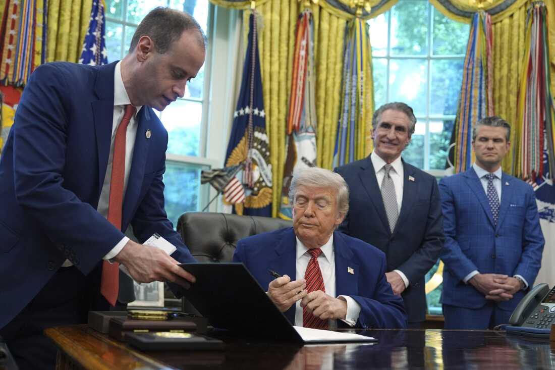 White House staff secretary Will Scharf hands President Donald Trump an executive order to sign regarding nuclear energy in the Oval Office of the White House, Friday, May 23, 2025, in Washington.