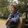 Vicky Stinson, a youthful looking 65-year-old, is pictured in profile, sitting on a part bench.