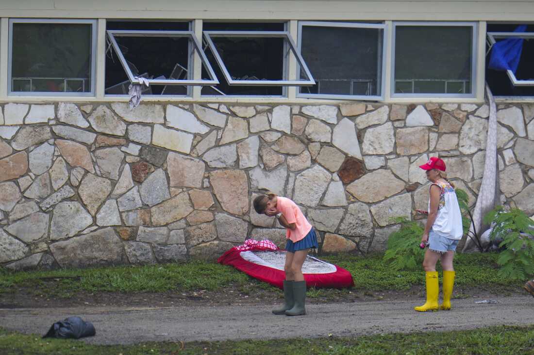 People react as they inspect an area outside sleeping quarters at Camp Mystic 