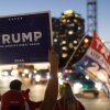 Supporters of Donald Trump, carrying flags and signs, march through a crosswalk in Virginia on November 8, 2024, expressing their excitement after his 2024 presidential election win.