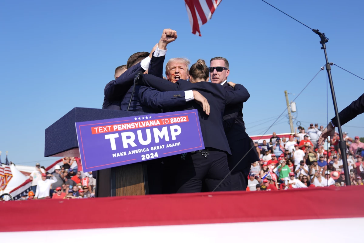 Trump holds a fist in the air as Secret Service agents surround him as he is rushed offstage at the campaign rally in Butler on July 13.