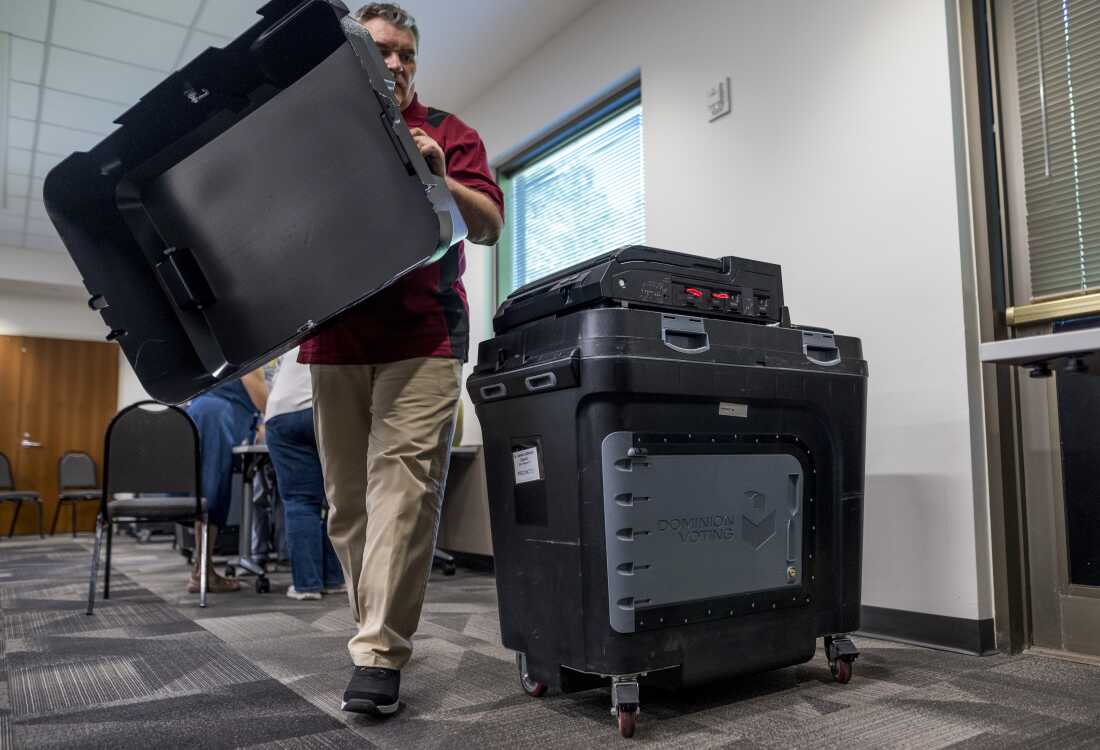 An election judge sets up a Dominion voting machine during a public accuracy test of voting equipment on Aug. 3, 2022, in Burnsville, Minn.