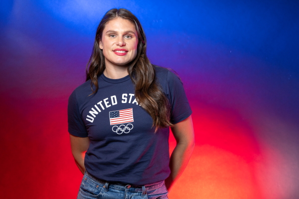 Ilona Maher, in an Team USA Olympics shirt, poses for a portrait against a red and blue background.