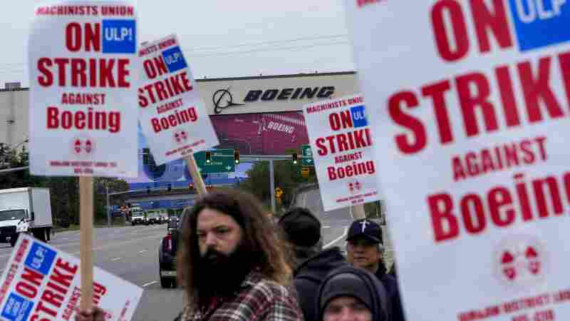 Boeing workers wave picket signs to passing drivers as they strike in Everett, Wash.. The machinists walked off the job more than six weeks ago as they bargain for higher pay and a return of their pension plan.