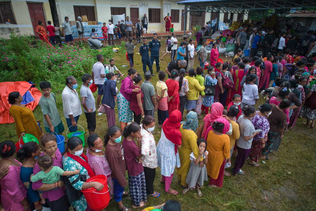 People affected by recent flash floods stand in line to receive aid at a school converted into a temporary shelter in Nepal’s Nuwakot district, Thursday.