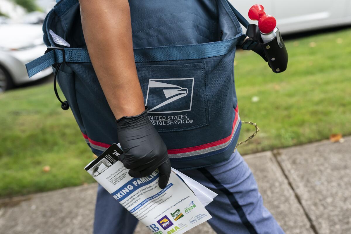 Letter carrier Connie Cruz delivers mail on Oct. 8, 2020, in Salem, Oregon. The U.S. Postal Service will continue to function should the government shut down.
