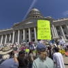 Protestocular, 23 Mayıs 2026'da Utah Salt Lake City'de Stratos veri merkezinin inşasına karşı çıkmak için Utah Eyaleti Meclis Binası önünde pankartlar tutuyor. Fotoğraftaki en belirgin işaret şu: