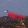 A tanker drops retardant as the Palisades Fire grows in the mountains in Topanga, Calif., on Thursday