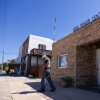 A man with a white beard is shown leaving a one-story brick building on a small town street. The building has a sign that reads, "Area Senior Center."