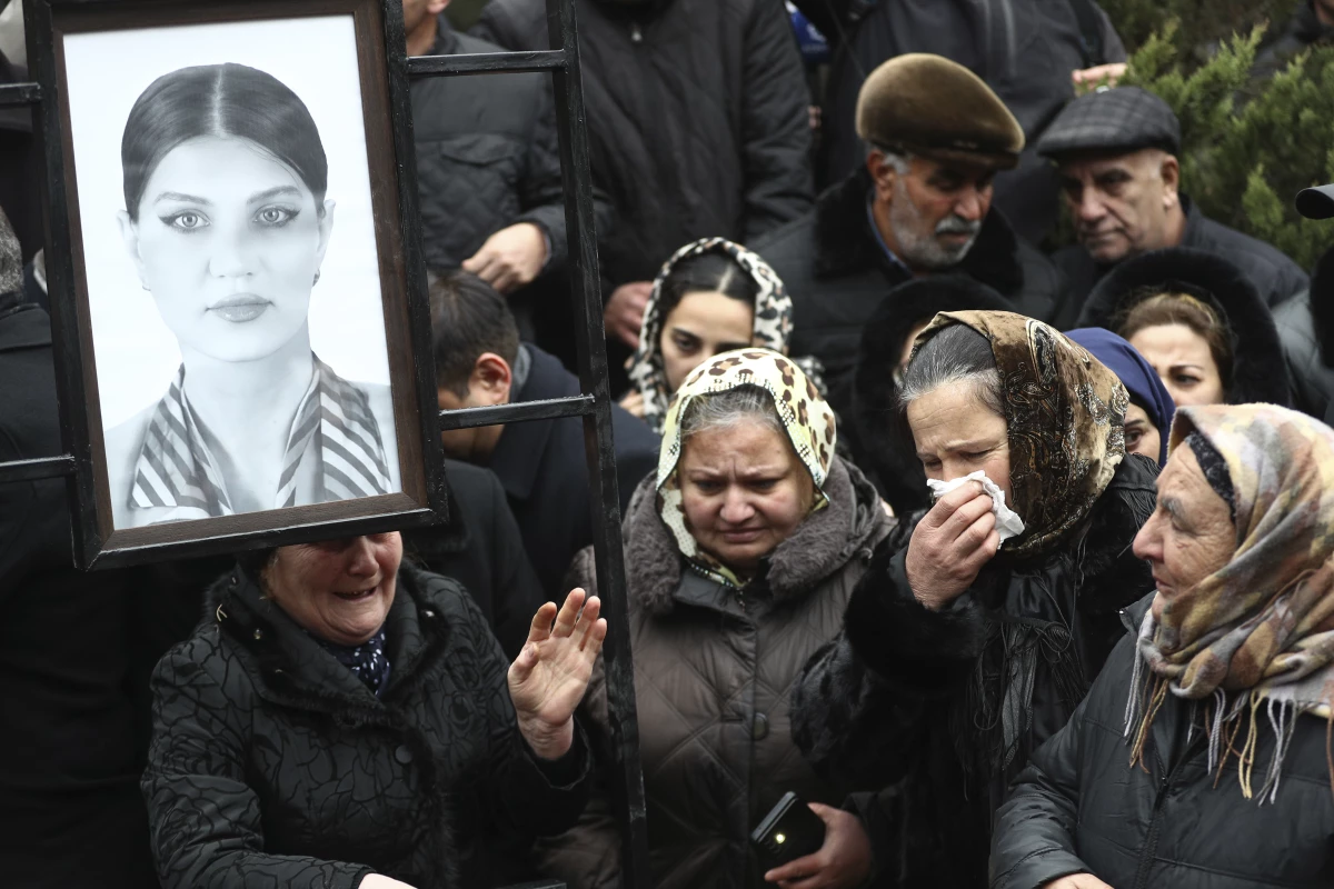 People mourn at the grave of flight attendant Hokume Aliyeva during a funeral of the crew members of the Azerbaijan Airlines Embraer 190 killed in a deadly plane crash in Kazakhstan this week, at the II Alley of Honor in Baku, Azerbaijan, Sunday, Dec. 29, 2024.