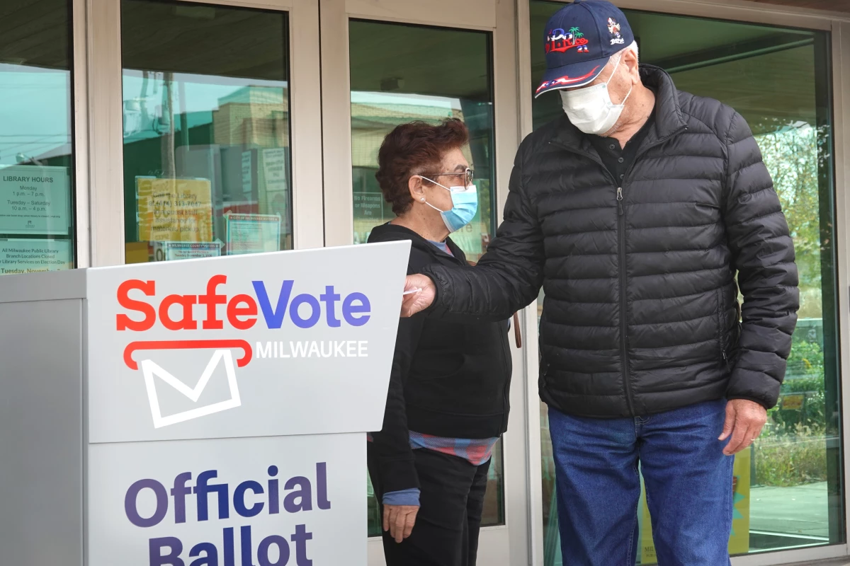 Wisconsin residents deposit mail ballots in a drop box outside of a library in Milwaukee on Oct. 20, 2020.