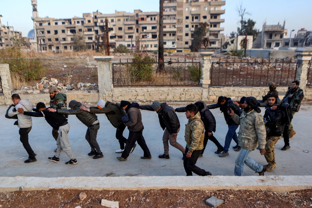 Syrian rebel fighters parade detained members of the Syrian government's forces in civilian clothing in Homs on Sunday, after rebel forces entered Syria's third city.