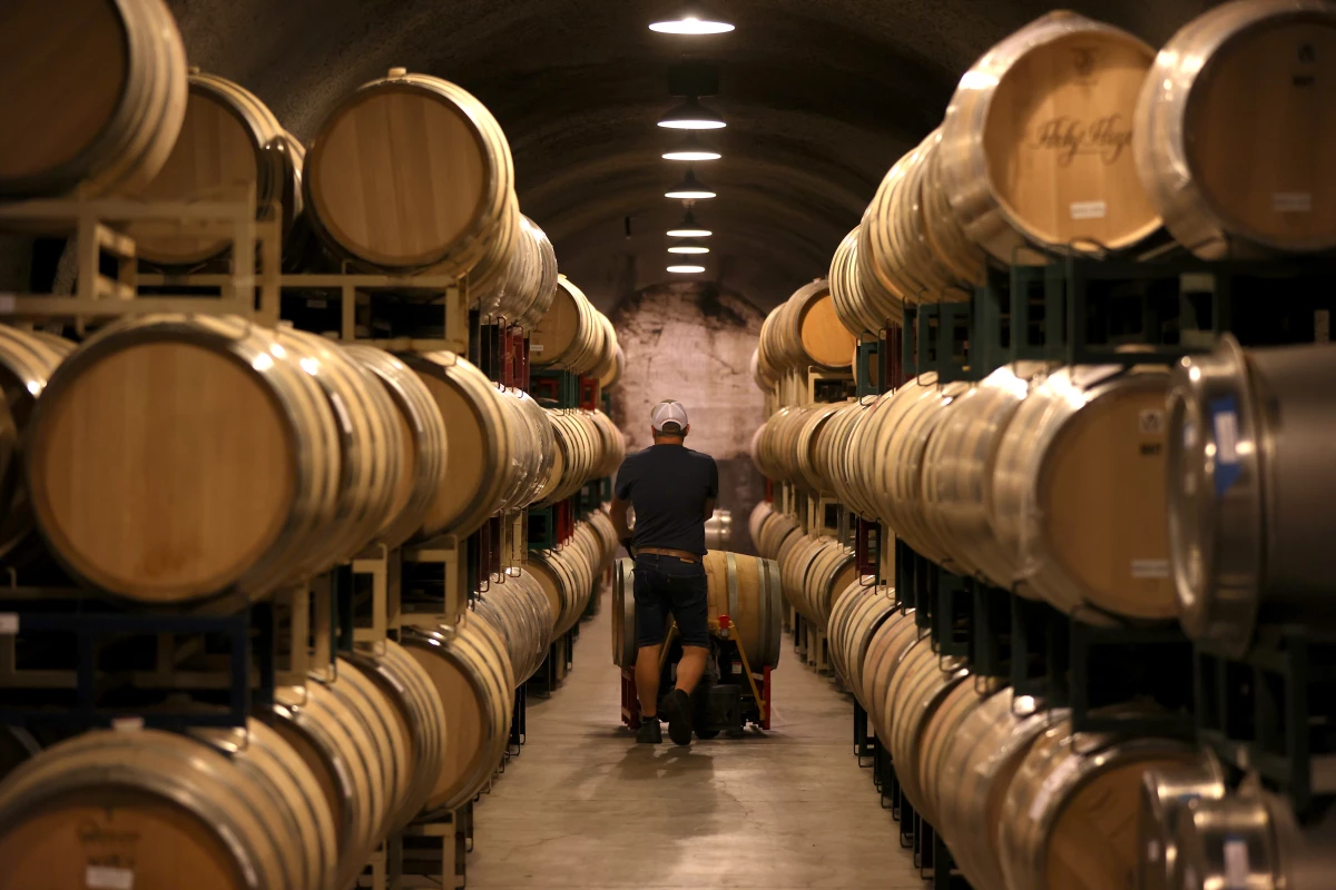 A worker pushes a wine barrel into a storage facility at Hunnicutt winery in St. Helena, Calif., on Sept. 30, 2021.
