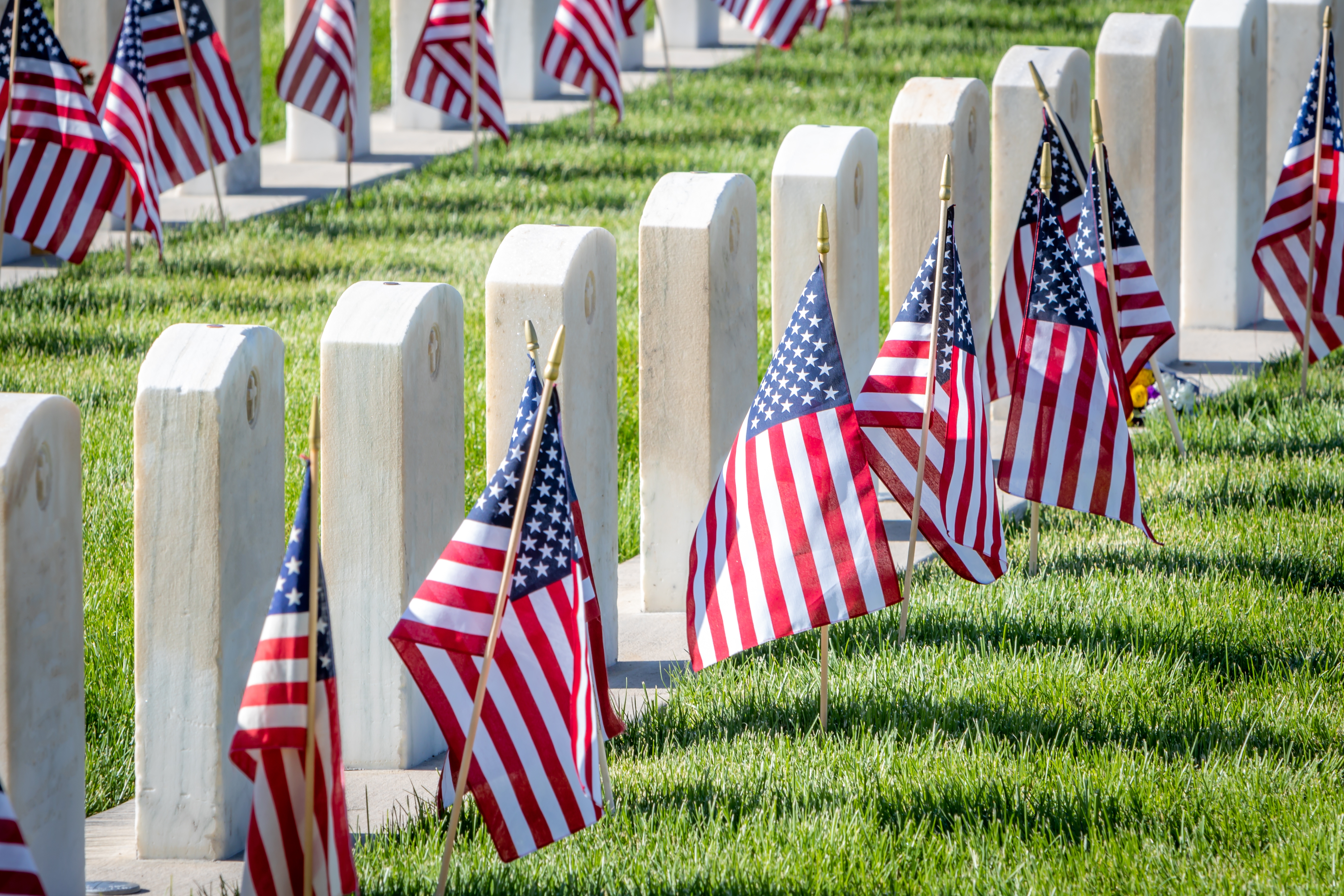 Military headstones honoring armed forces service members are decorated with American flags for Memorial Day.