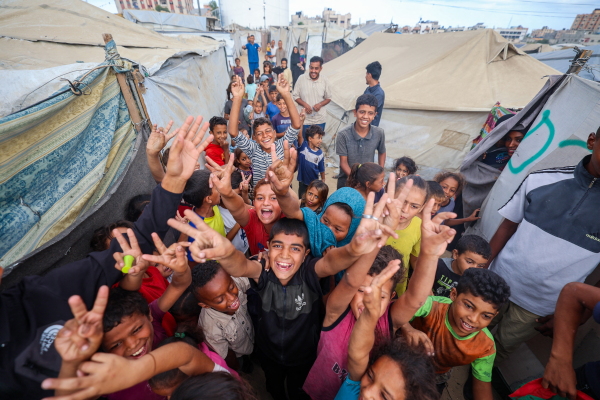 Palestinian children celebrate at a camp for displaced people in Nuseirat in the central Gaza Strip on October 9, 2025, following news of a new Gaza ceasefire deal.