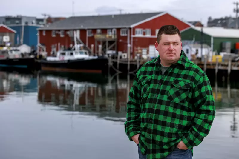 Fisherman Devyn Campbell stands near the water outside the Portland Fish Exchange. Boats and a marina are behind him.