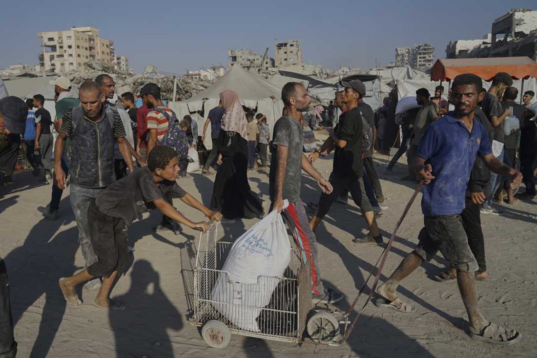 Palestinians carry sacks of flour unloaded from a humanitarian aid convoy that reached Gaza City from the northern Gaza Strip, Saturday, July 26, 2025.