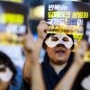 This photo shows activists wearing white eye masks and holding posters reading (in Korean) "Repeated deepfake sex crimes, the state is an accomplice too," during a protest against sexually abusive deepfakes in Seoul, South Korea, on Aug. 30.