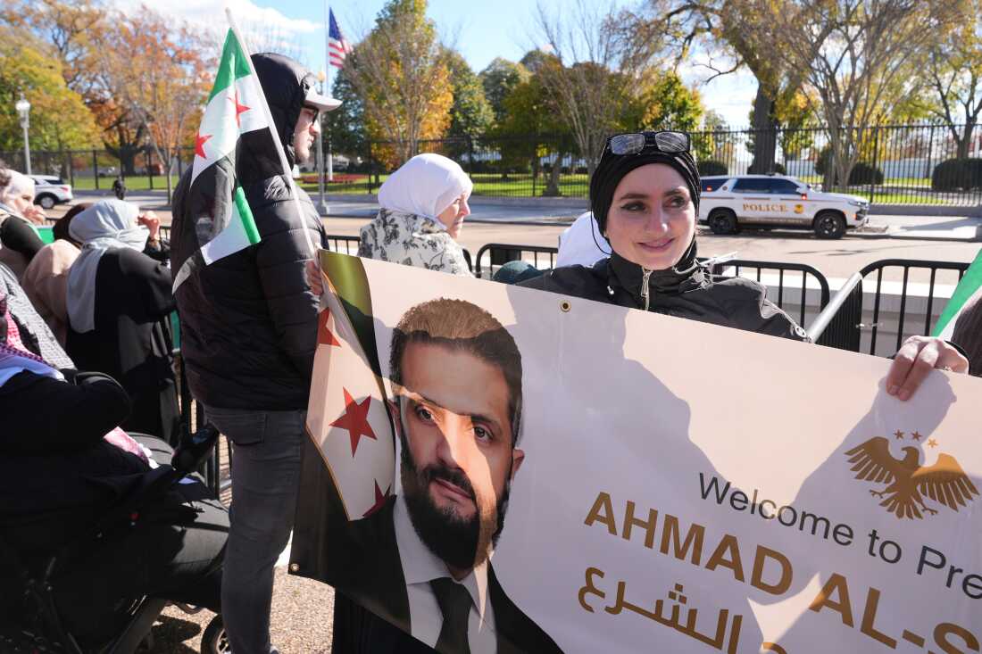 Motiah Boustany, of Charlestown, W.Va., holds a banner depicting Syria's President Ahmed al-Sharaa outside of the White House, as al-Sharaa meets with President Donald Trump, Monday, in Washington.