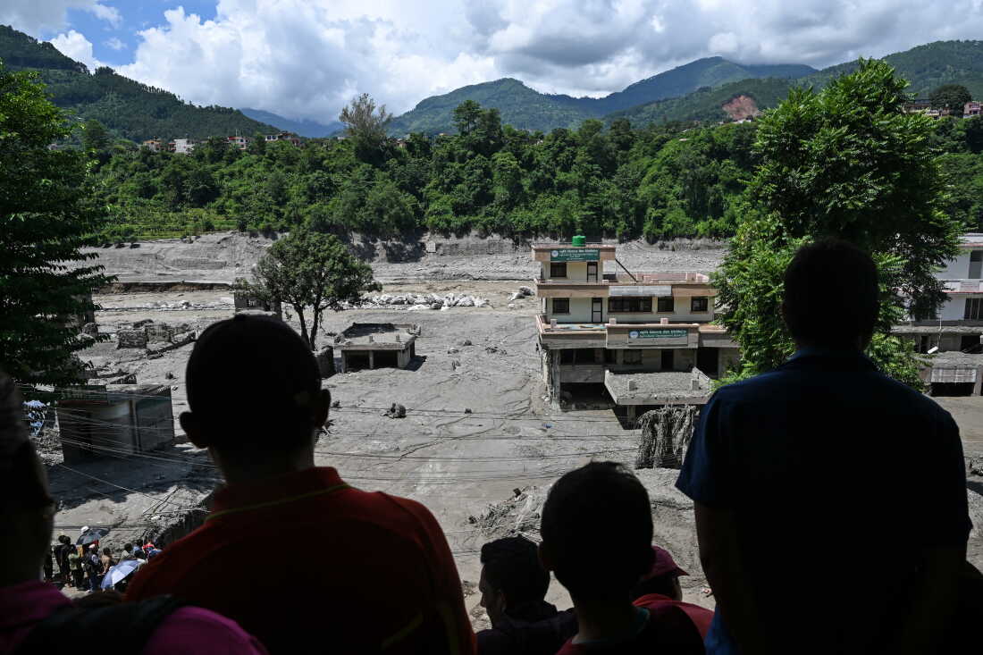 People watch from a rooftop as houses lay deluged in sludge after flash floods at Trishuli in Nepal's Nuwakot district.