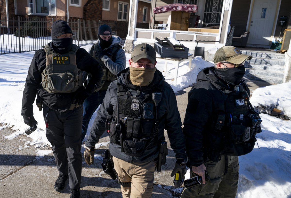 Masked ICE agents leave a residence after knocking on the door in Minneapolis on Wednesday.