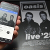 A fan uses a smartphone to access an online ticket sales website to purchase tickets for Oasis' "Live '25" tour. Oasis fans queued online early Saturday to buy tickets for the eagerly awaited reunion tour, but many tickets had already been scooped up by resellers charging many times over original ticket prices.