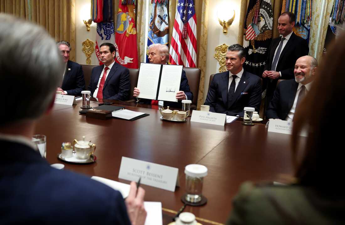 President Trump holds up a presidential proclamation for Columbus Day during a Cabinet meeting at the White House on Thursday.