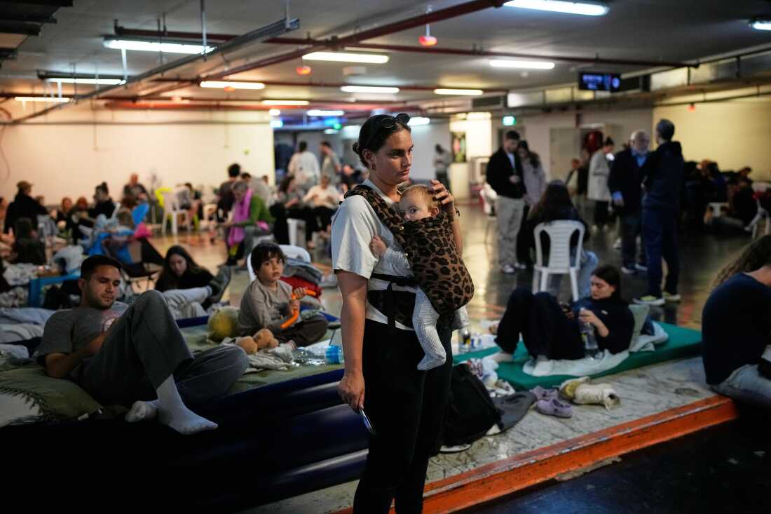 Leah Guttmann holds her son, Teddy, as other people take shelter in an underground parking garage while air-raid sirens warn of incoming missiles launched by Iran toward Tel Aviv, Israel, Sunday, March 1, 2026.