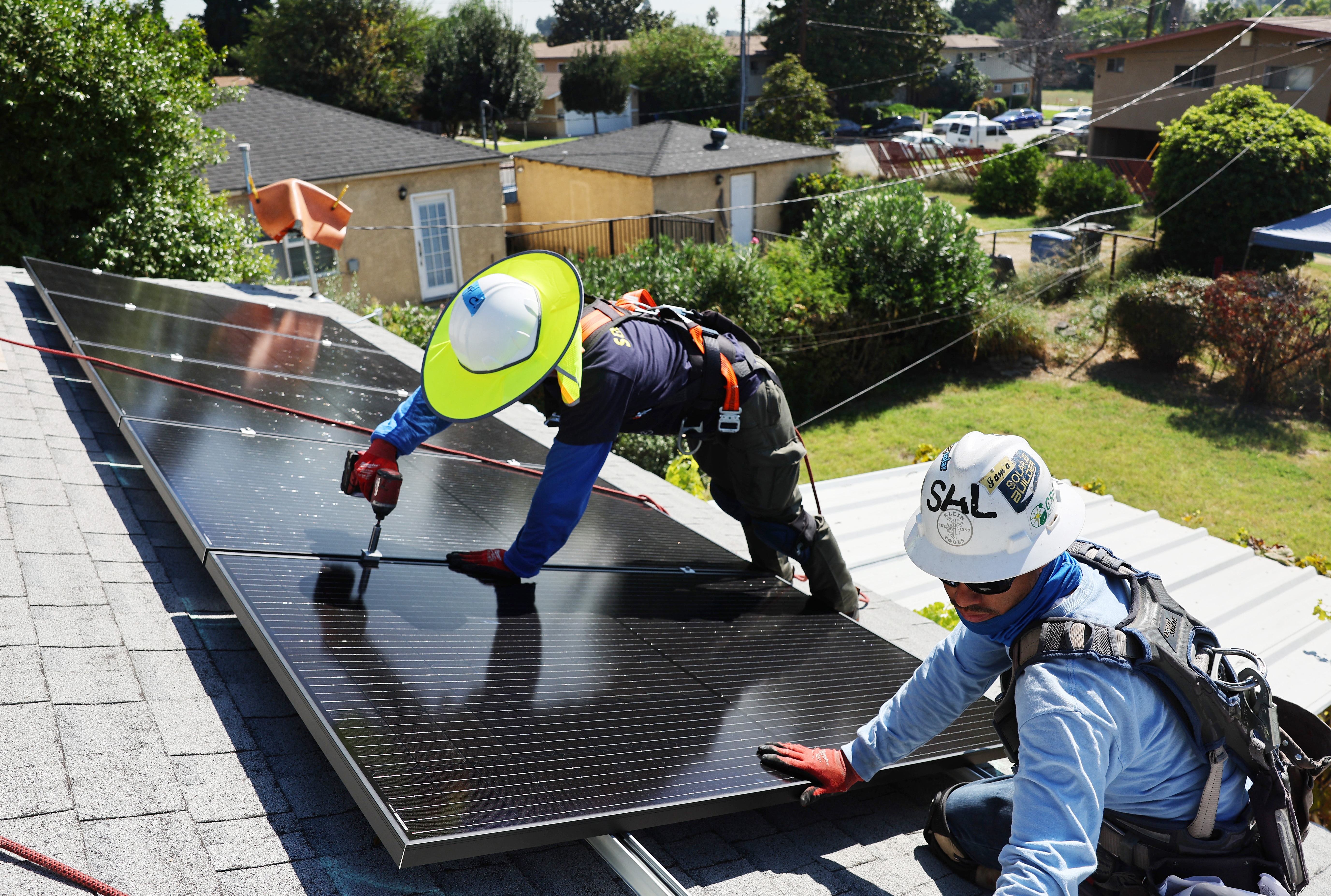 GRID Alternatives employees install no-cost solar panels on the rooftop of a low-income household on October 19, 2023 in Pomona, California.