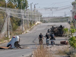 Ukrainian troops ride bikes under anti-drone netting in the front-line town of Druzhkivka, Ukraine, on Sept. 12. Both the Russian and Ukrainian forces have put up nets to guard against drones. The troops often move on foot or on bikes because tanks, armored personnel carriers and other military vehicles are easily spotted and often attacked.