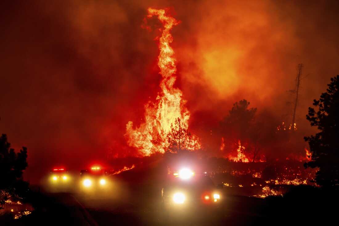 Flames leap above fire vehicles near Paynes Creek in Tehama County, Calif.