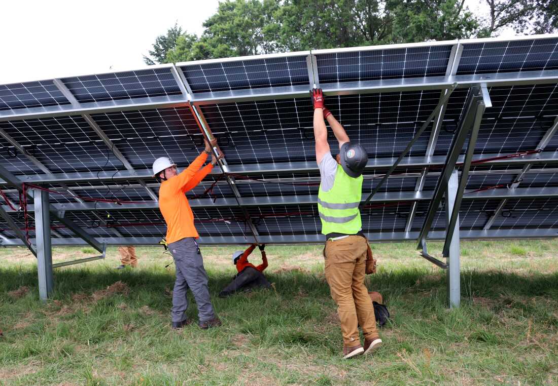 Two workers put together a solar panel that's part of a community solar project in Portland, Oregon.