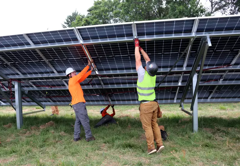 Two workers put together a solar panel that's part of a community solar project in Portland, Oregon.